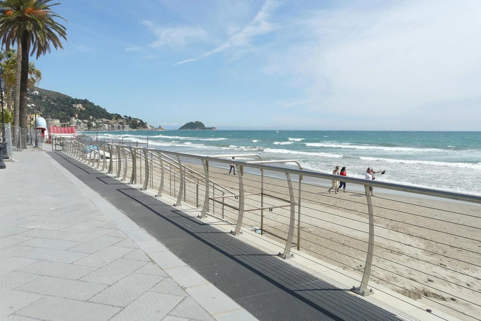 La passeggiata a mare di Alassio con palme, spiaggia e l'isola Gallinara sullo sfondo