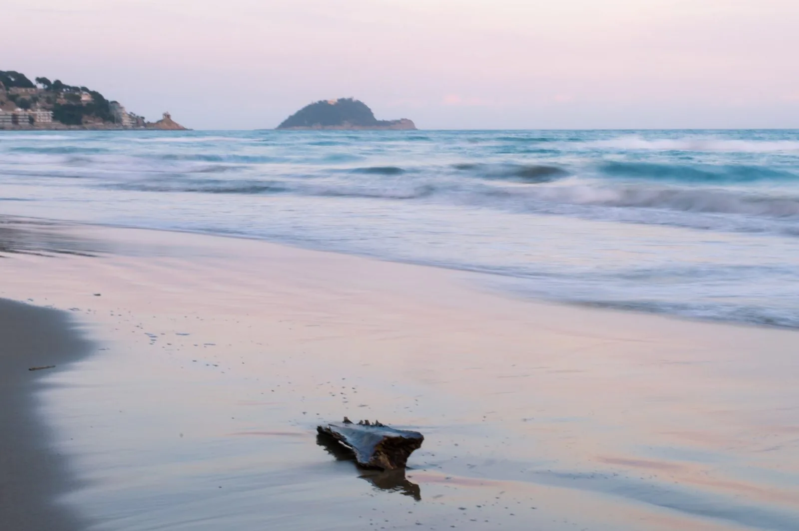 Spiaggia di sabbia di Alassio al tramonto con l'isola Gallinara sullo sfondo